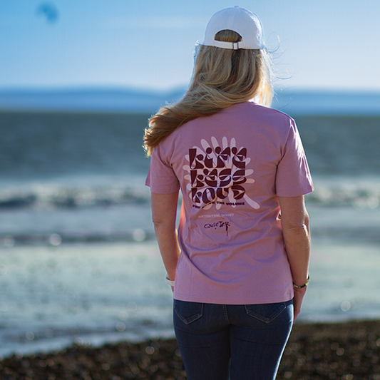 Person wearing a pink t-shirt with text at the beach