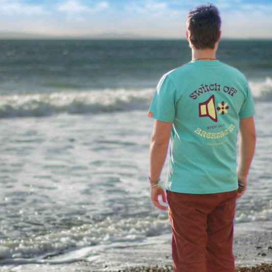 Person wearing QUIETER Switch Off tee in retro reef, back view outdoors