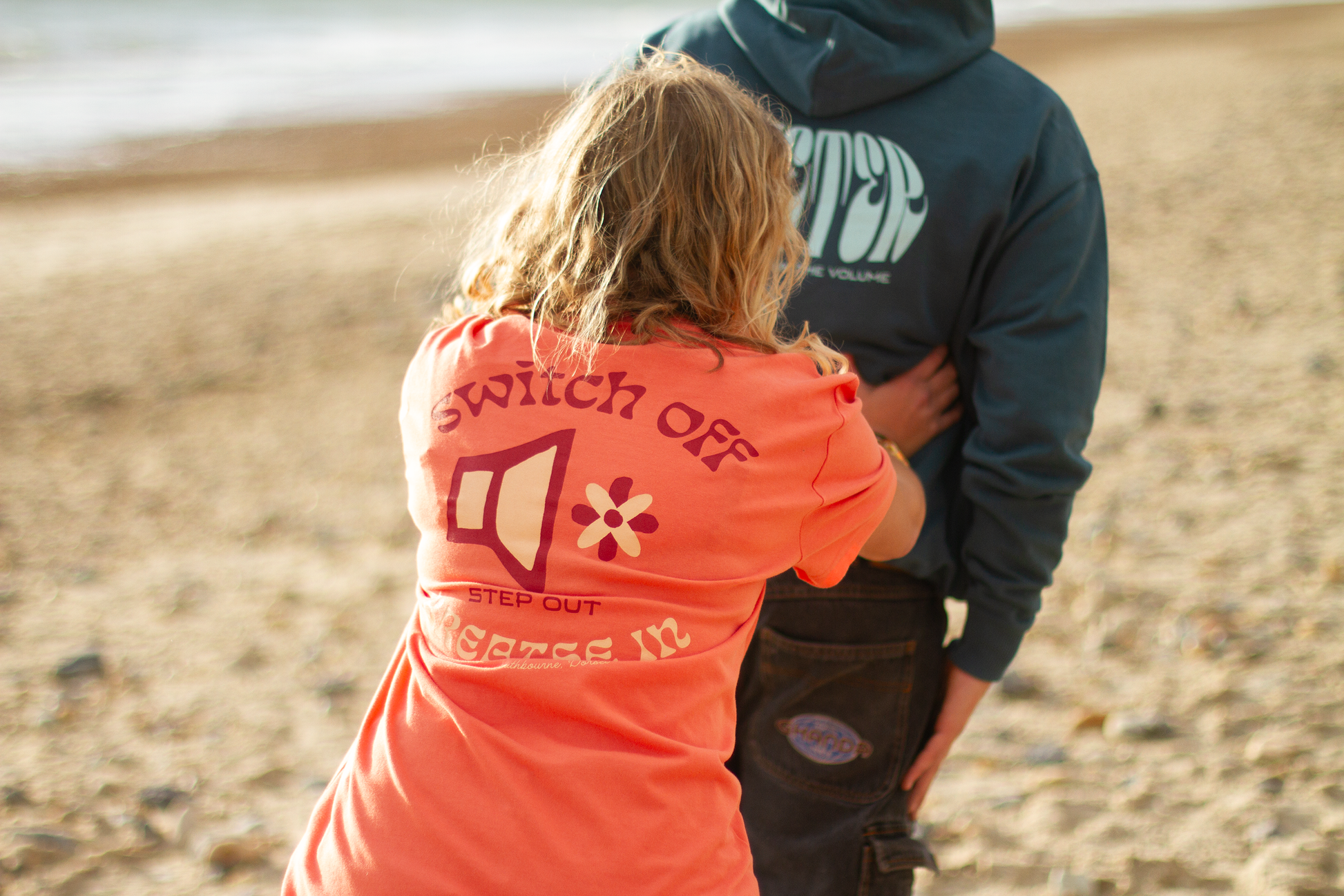 Person wearing an orange 'Switch Off' tee on a beach